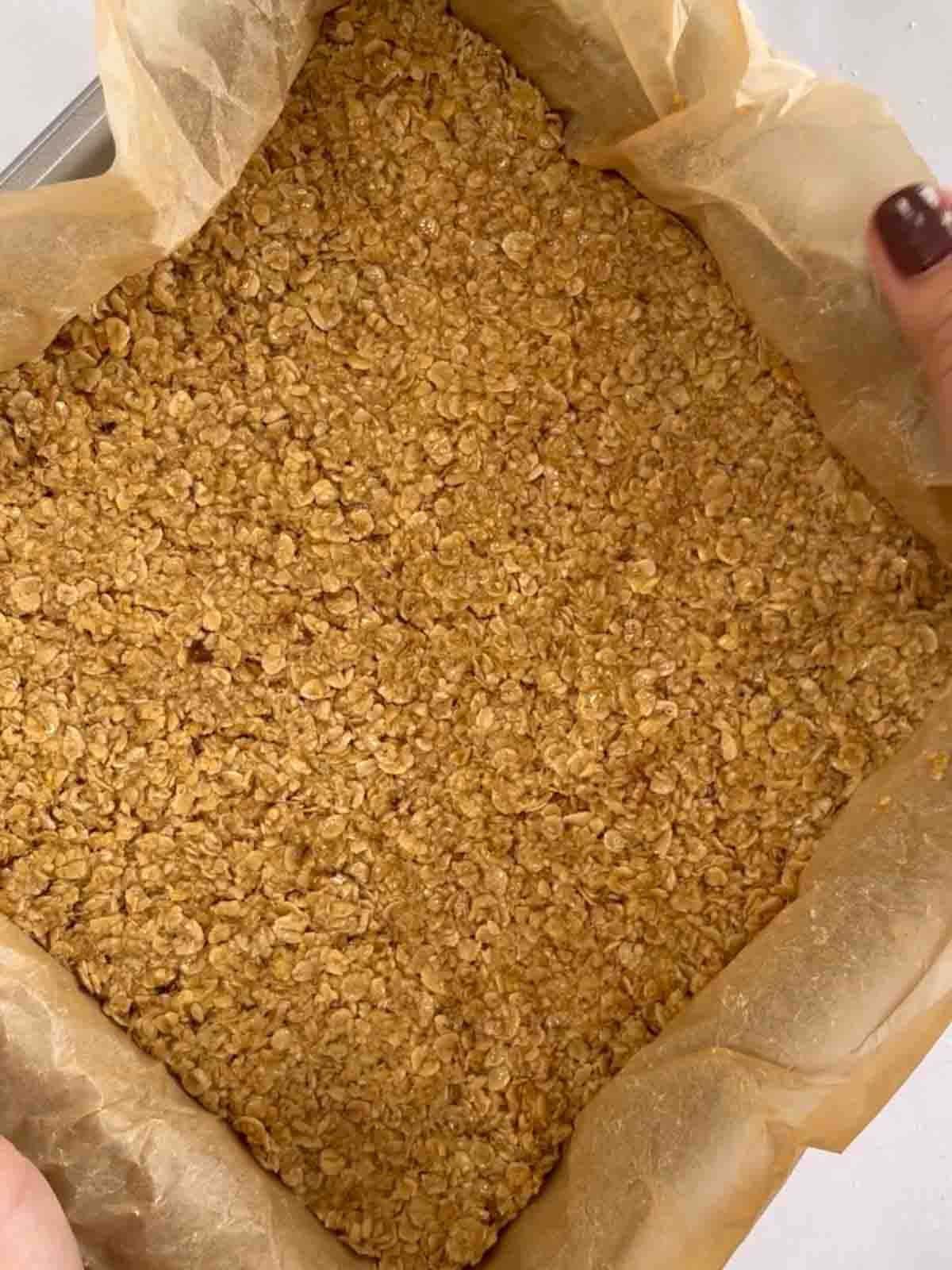 Oat mixture pressed into a baking tray for step 3 in the recipe for flapjacks.