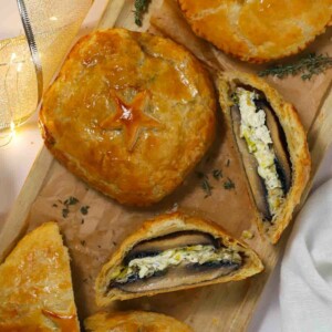 A board with lights and ribbon and a wooden board with cooked mushroom wellingtons on, with one showing the filling inside.