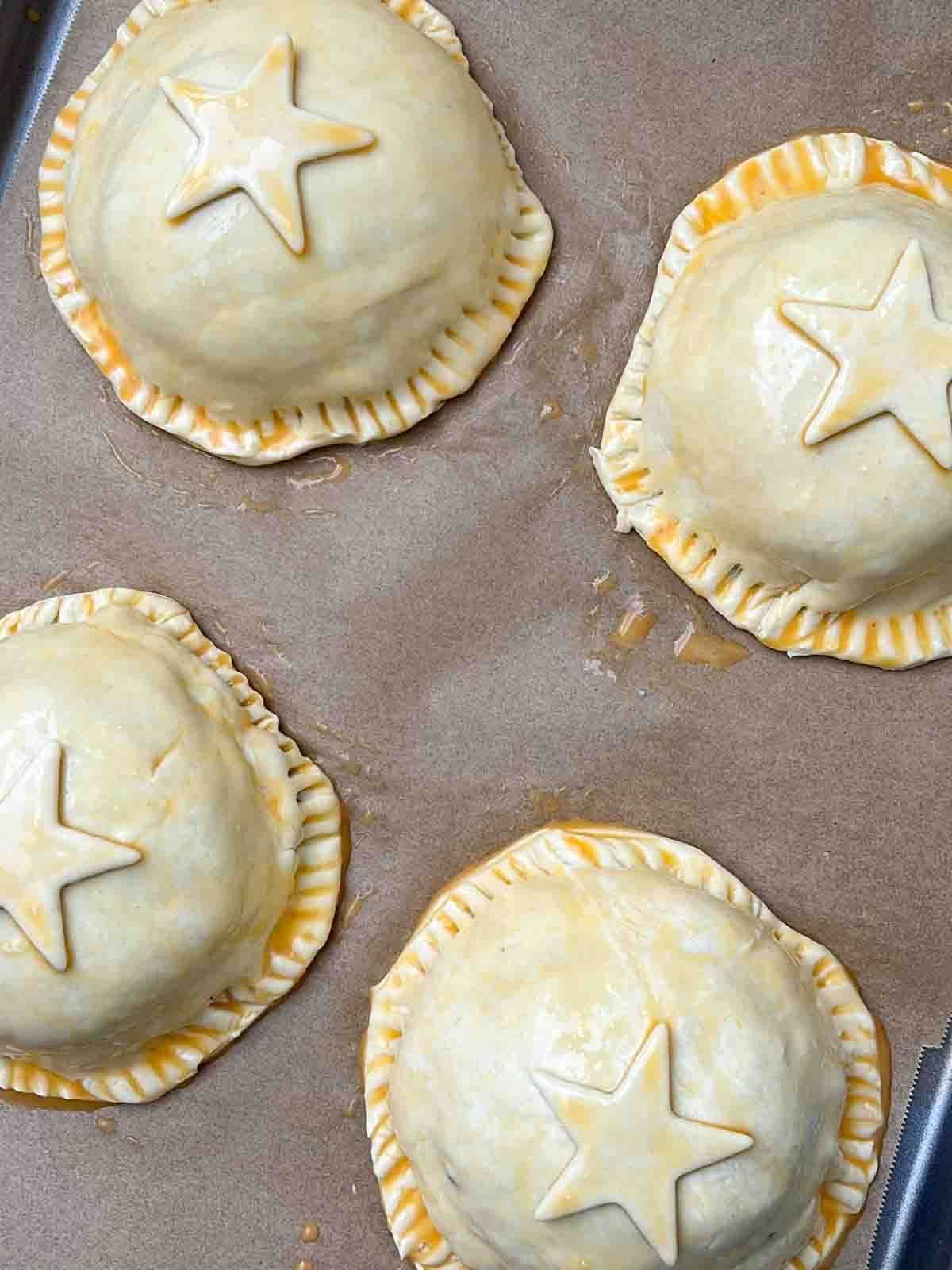 Four uncooked mushroom wellington parcels with a pastry star on top to decorate, ready to go in the oven.