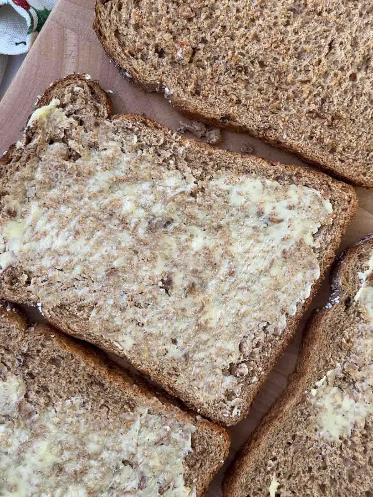 Slices of buttered brown bread on a chopping board for step 1 in the recipe for Smoked Salmon Canapes.