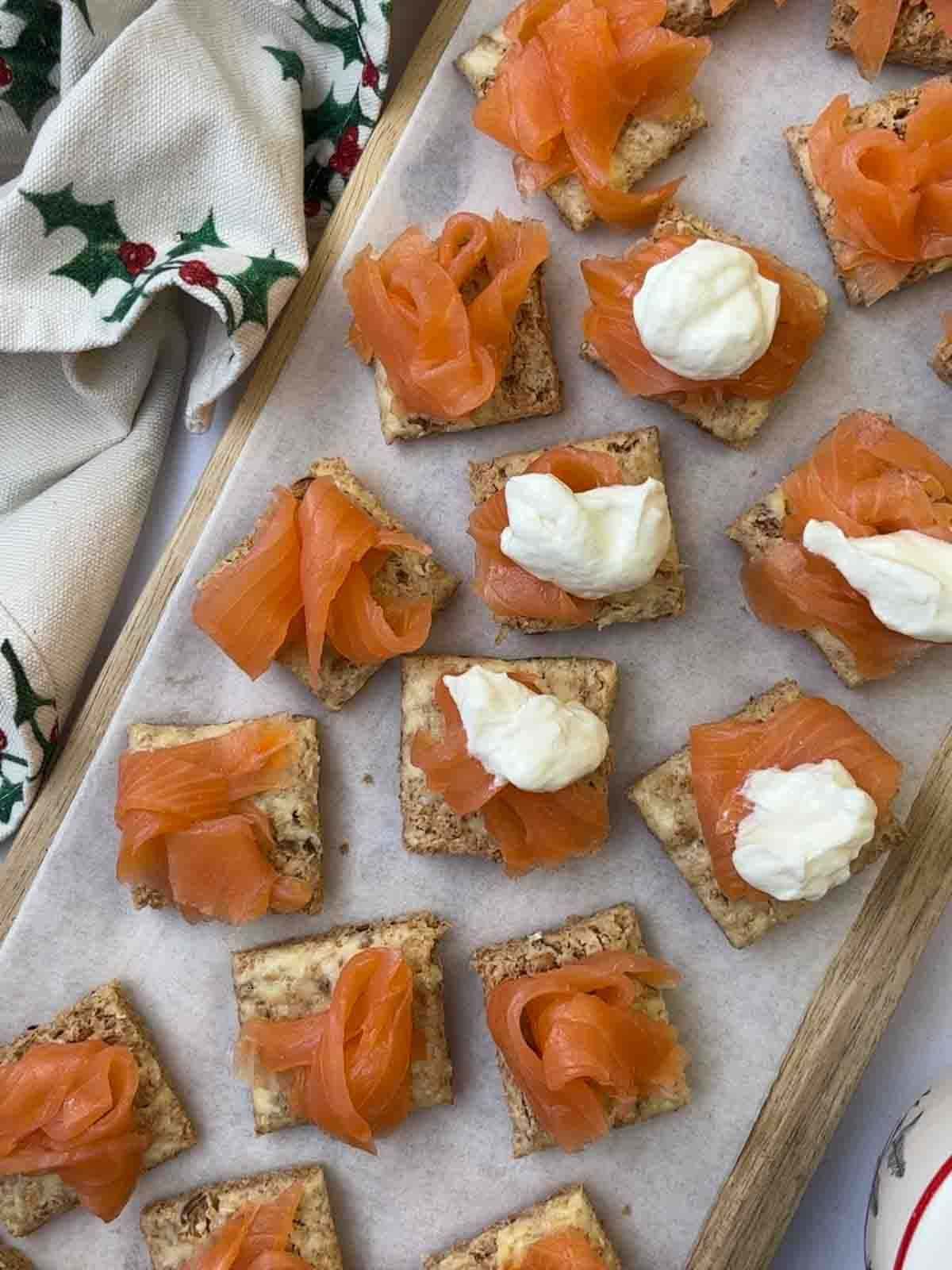 Smoked Salmon Canapes on a plate being topped with salmon and creme fraiche.