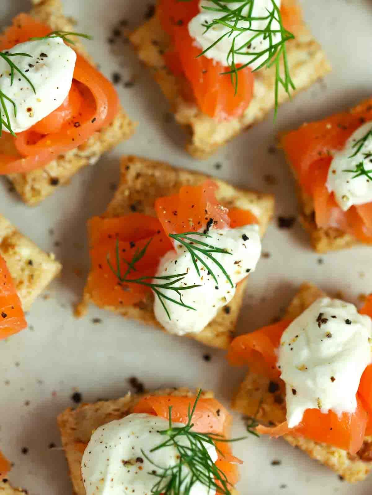 A serving board filled with squares of Smoked Salmon Canapés.