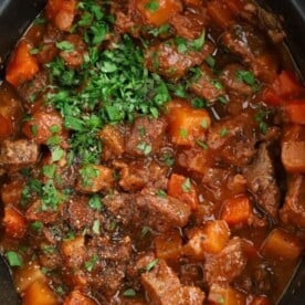 A slow cooker pan filled with cooked beef stew with a rick gravy and vegetables.