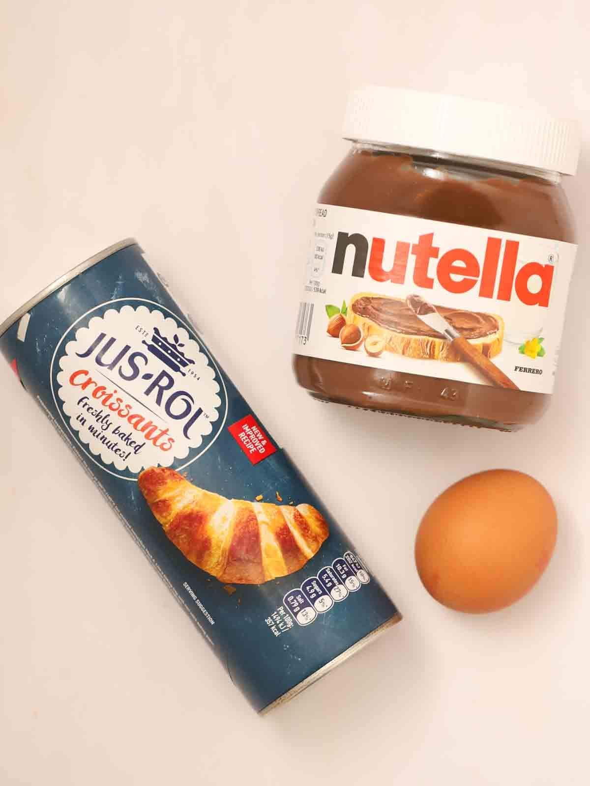 A bird's eye view of three ingredients - a jar of nutella, croissant pastry and one egg. Ingredients for the recipe Nutella Christmas Tree.