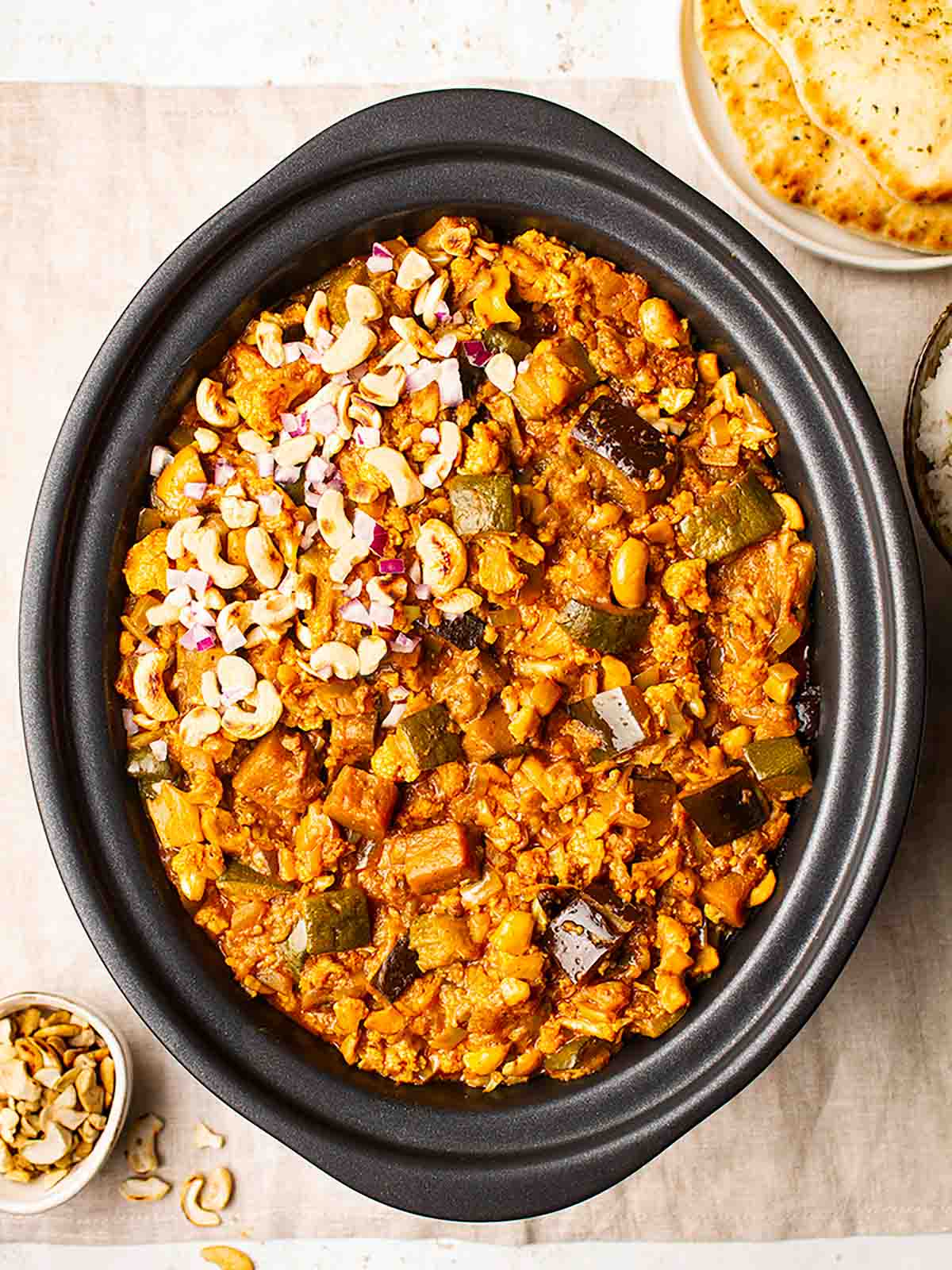 Vegetarian slow cooker curry in a slow cooker topped with cashew nuts.