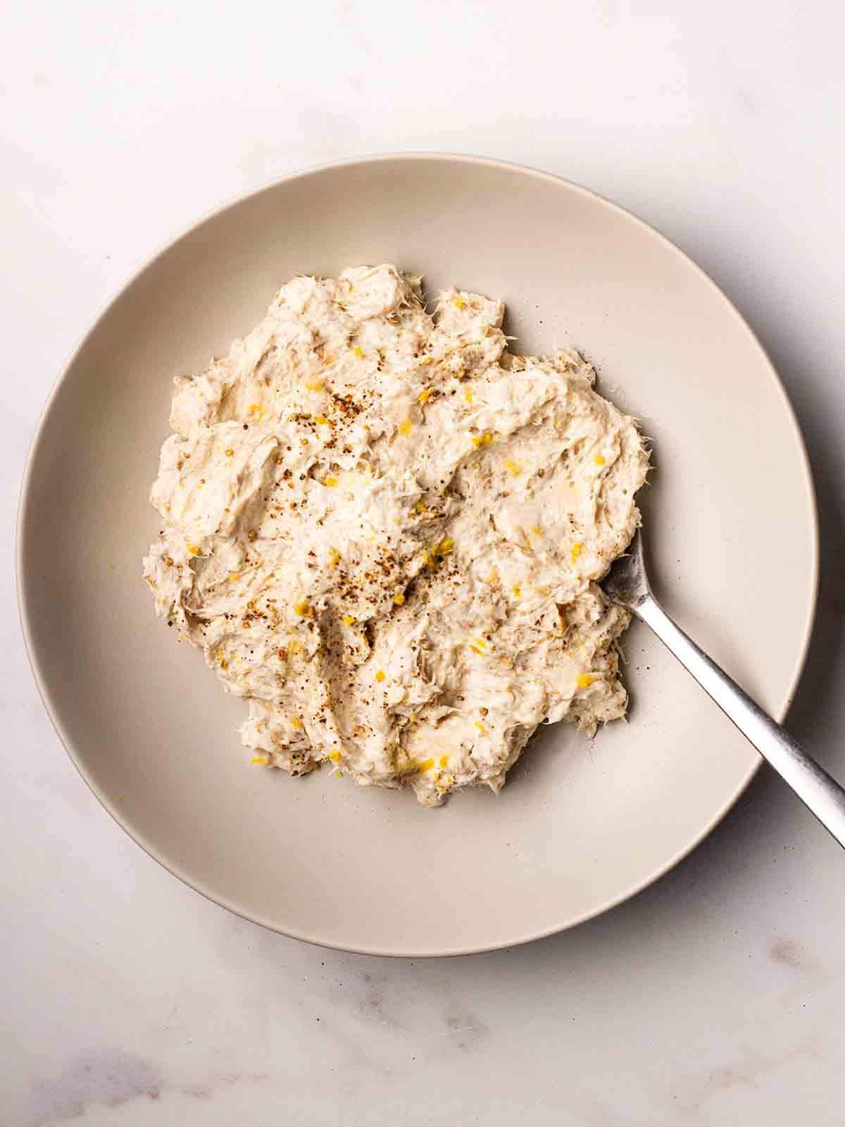 A plate with mackerel pate and a fork, ready to be served.