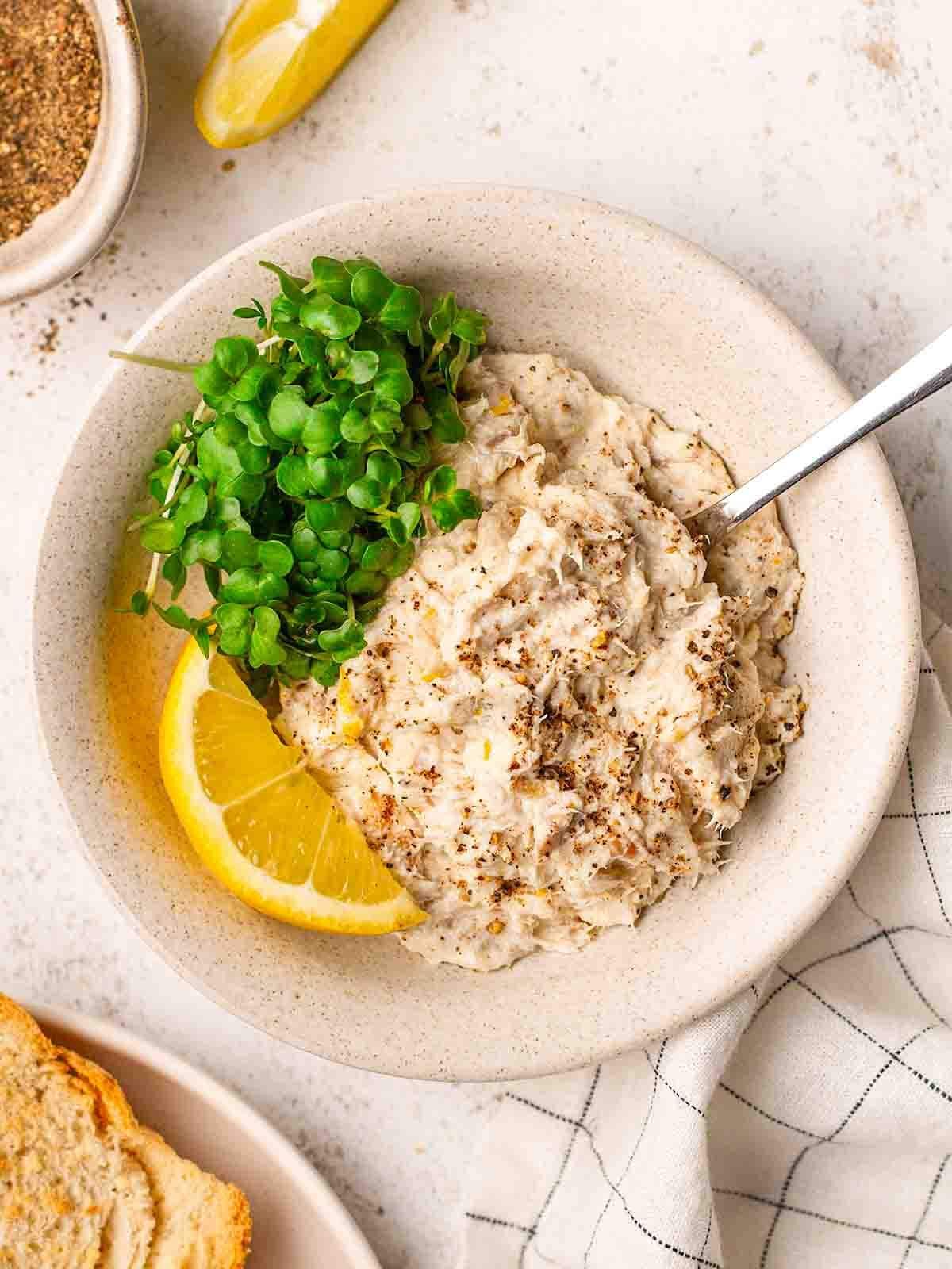 Mackerel Pate on a plate with salad and a wedge of lemon, on a table ready to eat.