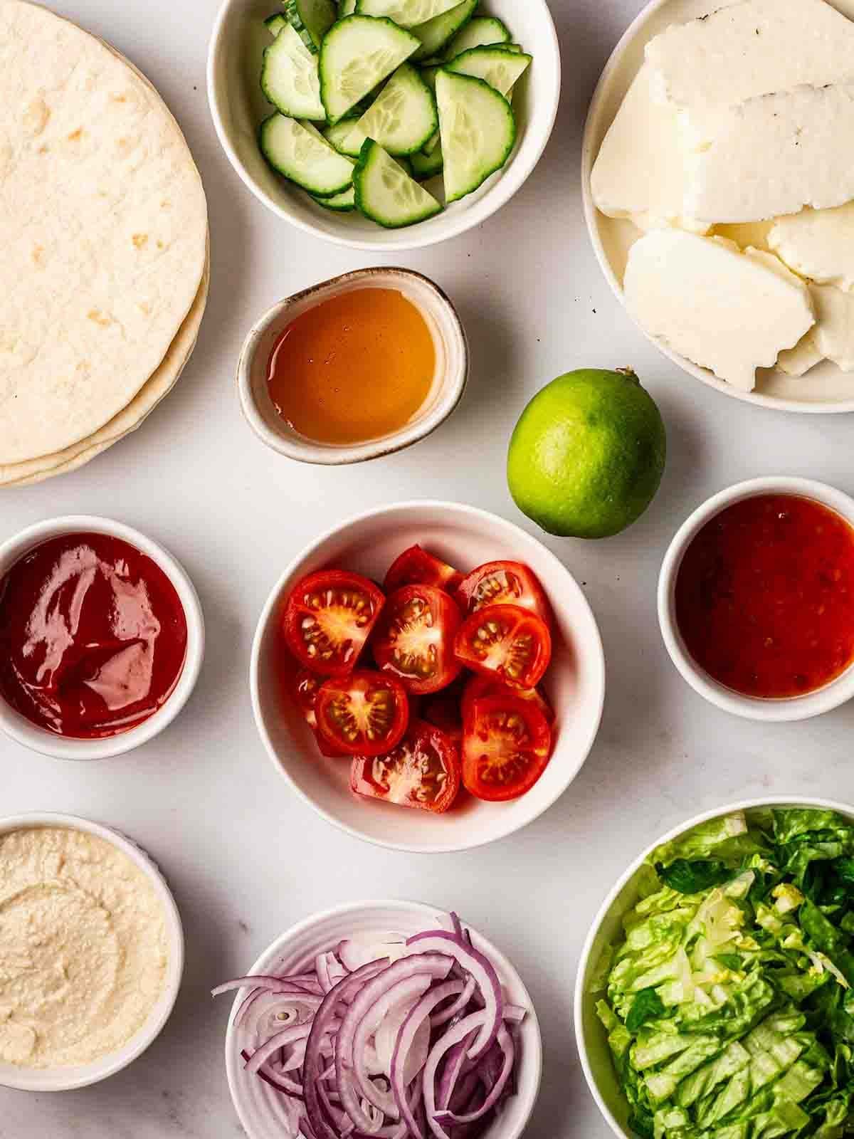 The ingredients for Halloumi Wraps laid out on a counter top in individual bowls.