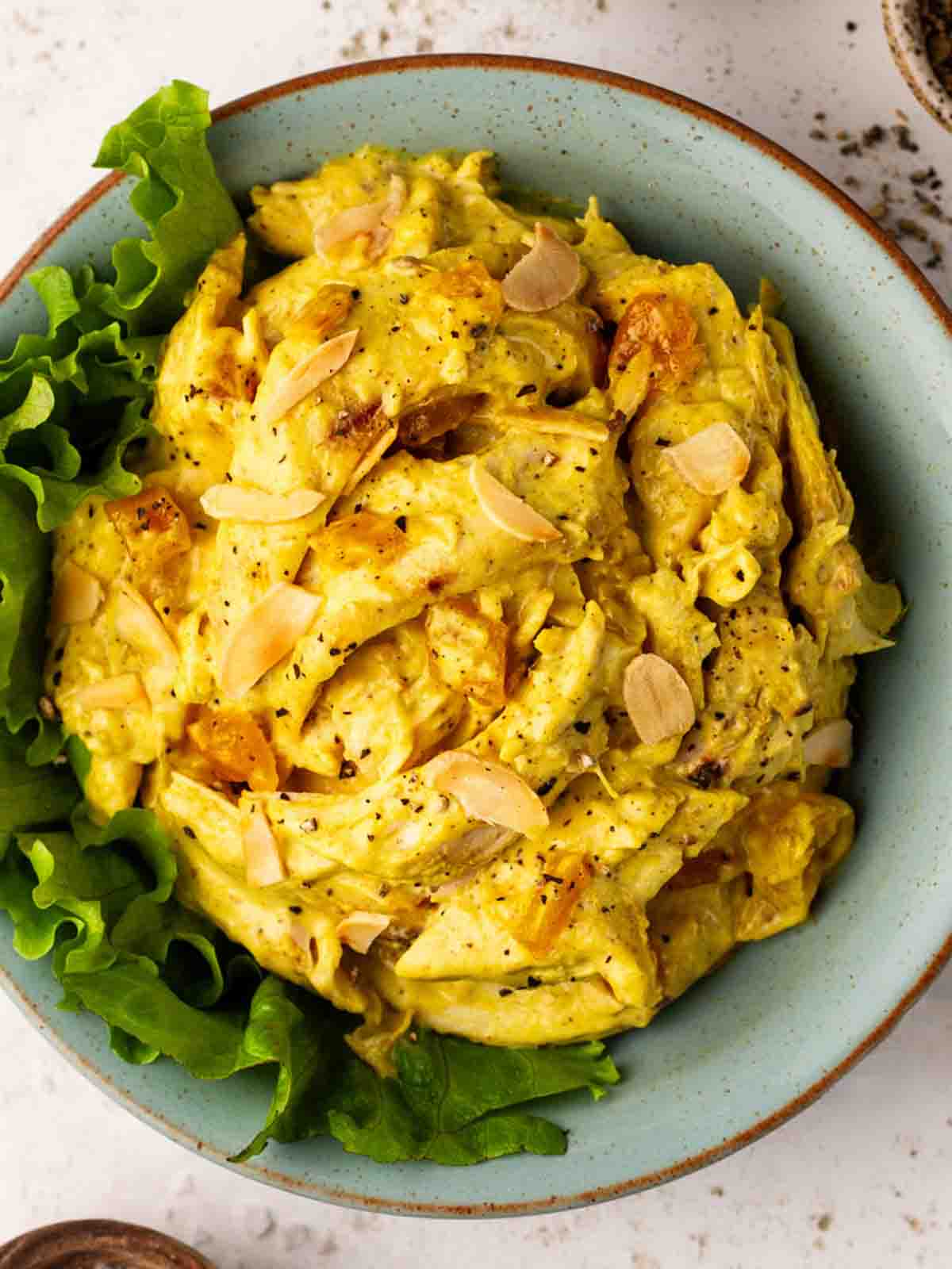 A bowl filled with lettuce and Coronation Chicken on top, with almond flakes to finish.