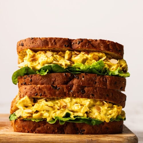 Two sandwiches filled with Coronation Chicken on a board.
