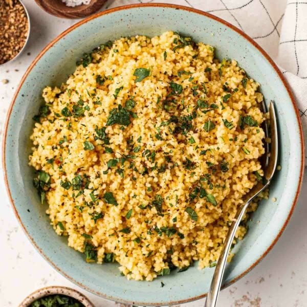 A bowl filled with cous cous and a fork.