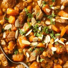 A close up of lamb, butternut squash, mint and onion, cooked together in a sauce to make up a Lamb Tagine.