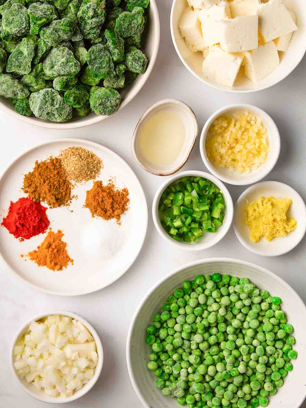 Bowls of ingredients on a counter top for the recipe Palak Paneer.