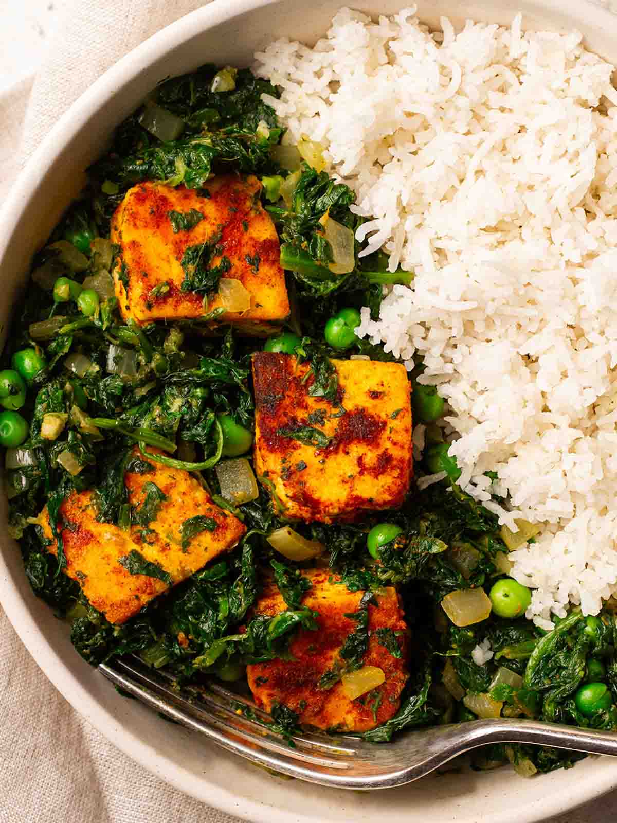 A bowl of Palak Paneer curry and rice, with a fork.