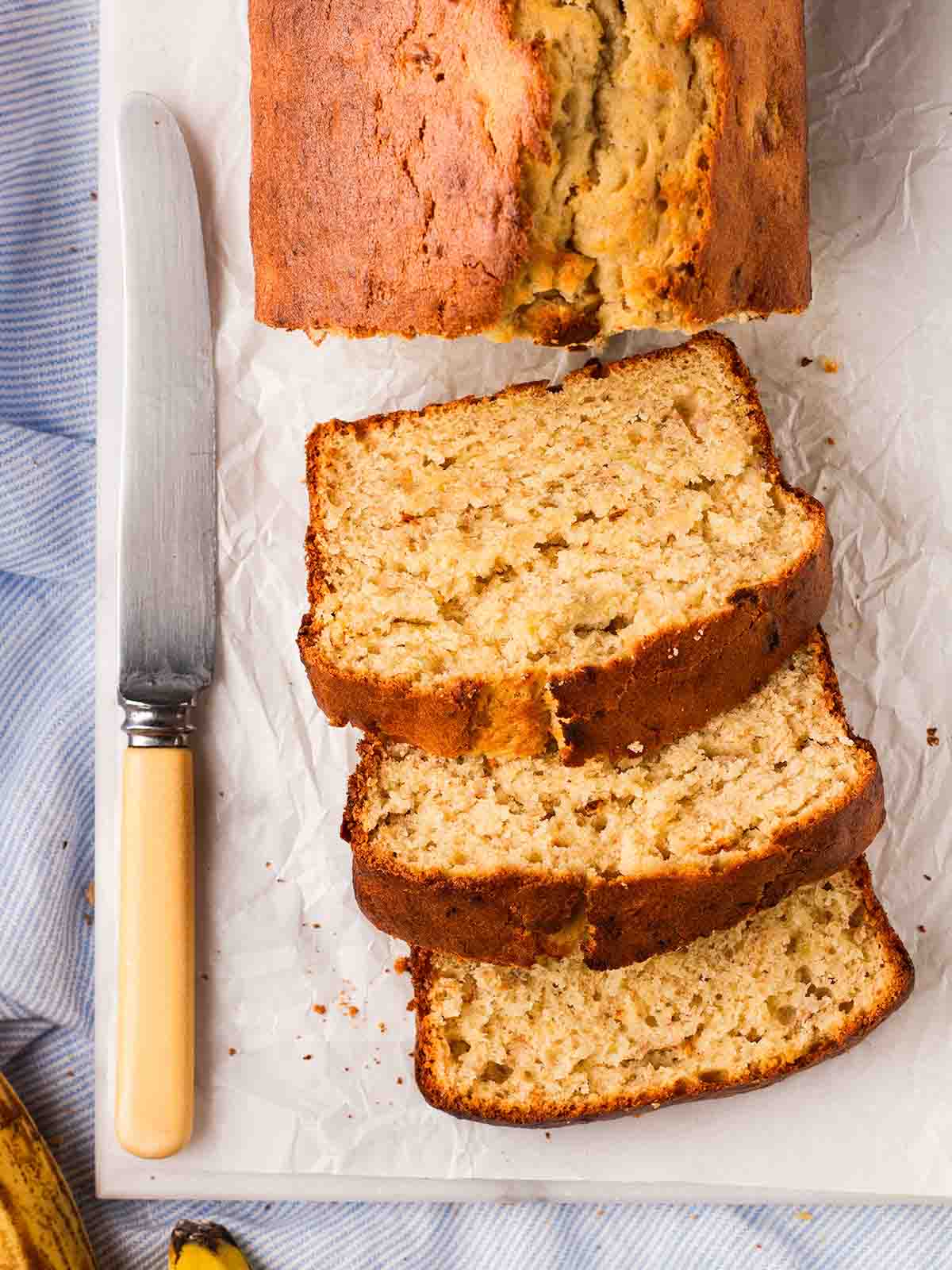 A sliced banana cake on a plate with a knife to the side.