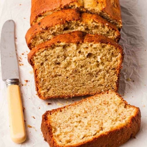 A banana loaf with 3 sliced pieces, on a table.