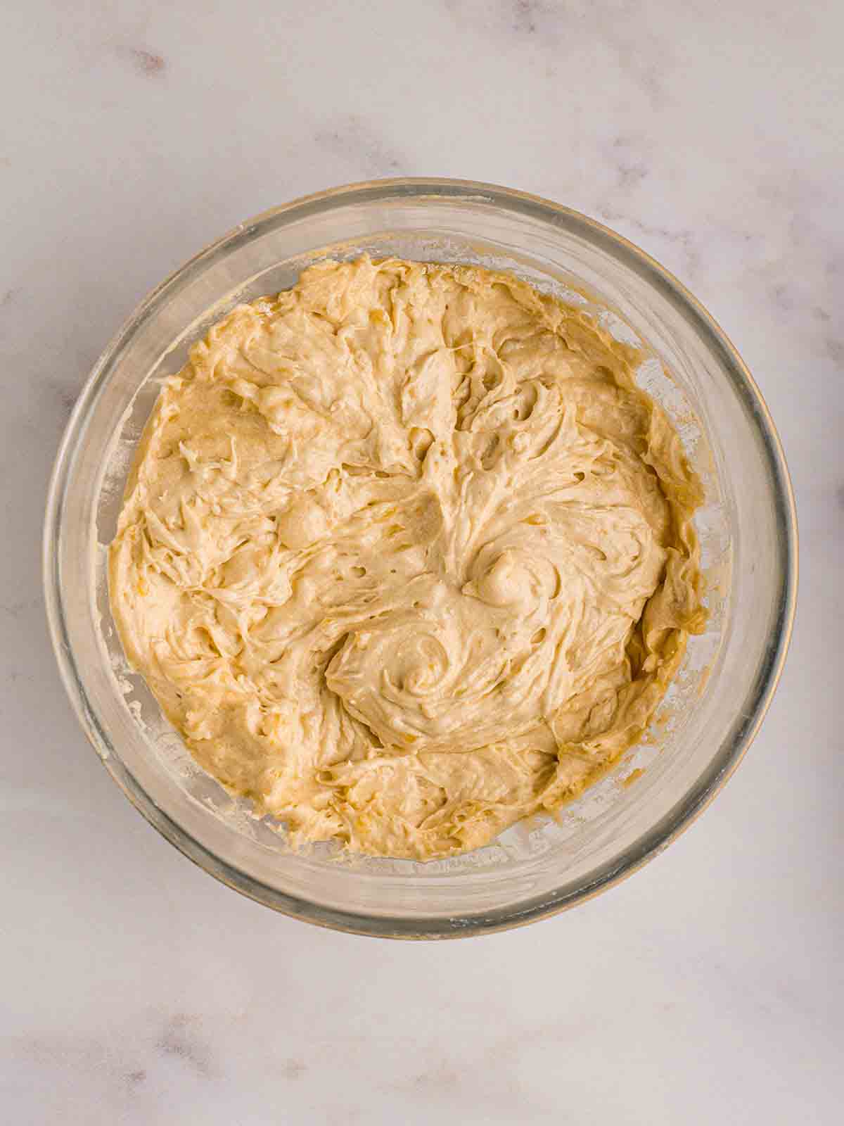 A glass bowl filled with cake mixture for step 2 in the recipe for Banana Cake.