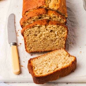 A square image of a sliced banana cake next to a knife.