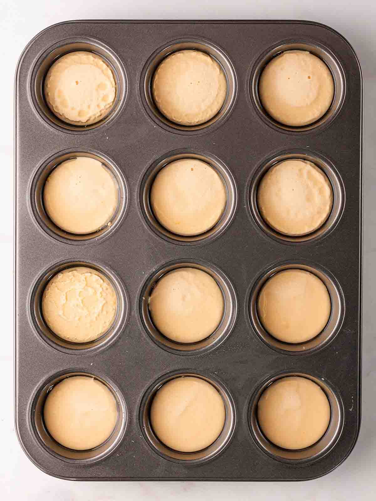 A muffin tray with each hole filled with Yorkshire Pudding batter.