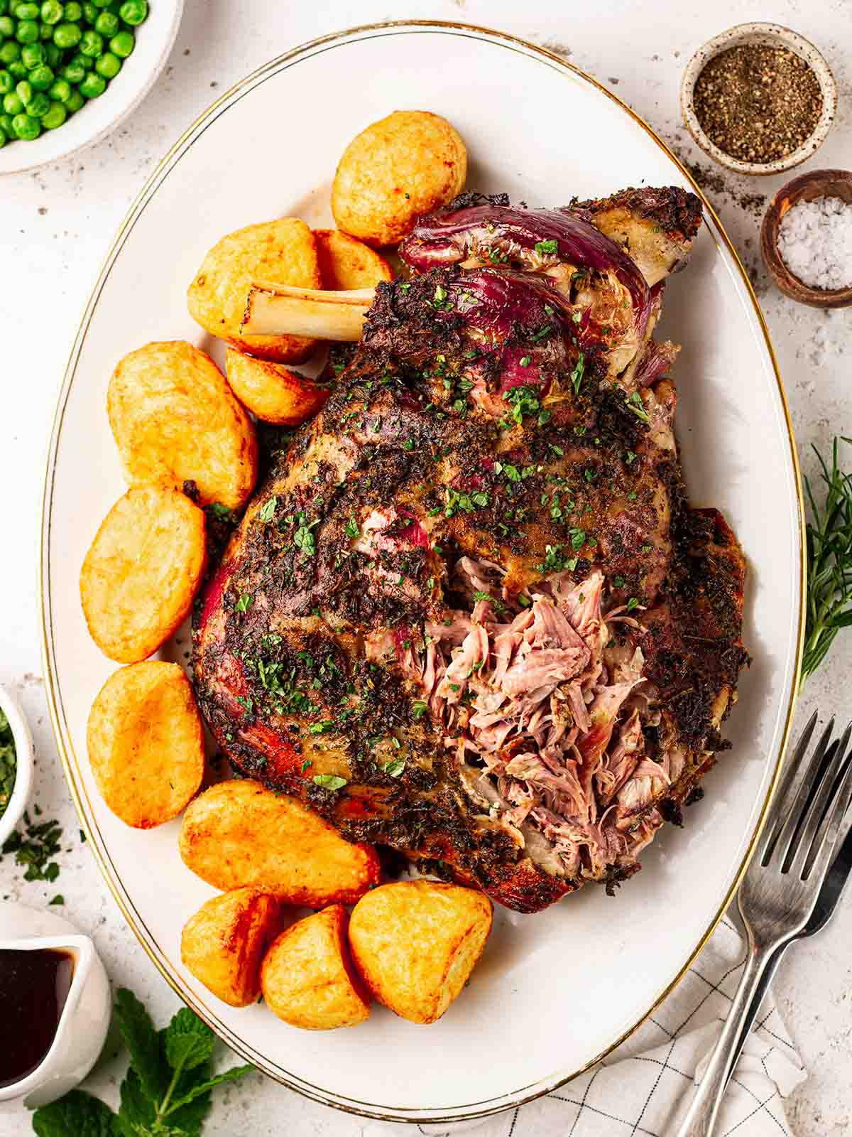 A large serving plate with roast potatoes and slow roasted shoulder of lamb, ready to serve.