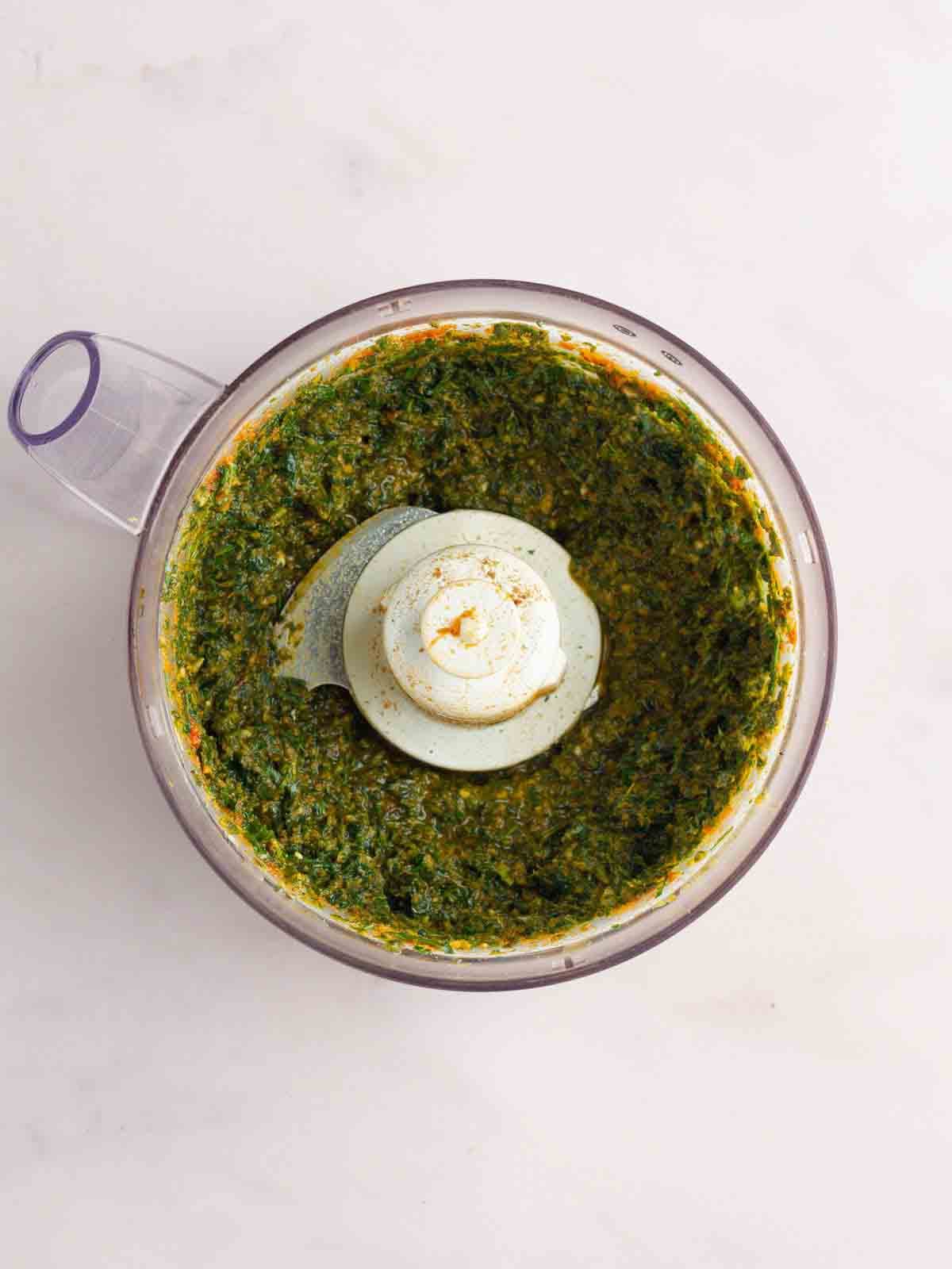 A food processor with a green herb mixture, ready to be rubbed onto a slow roasted lamb shoulder.
