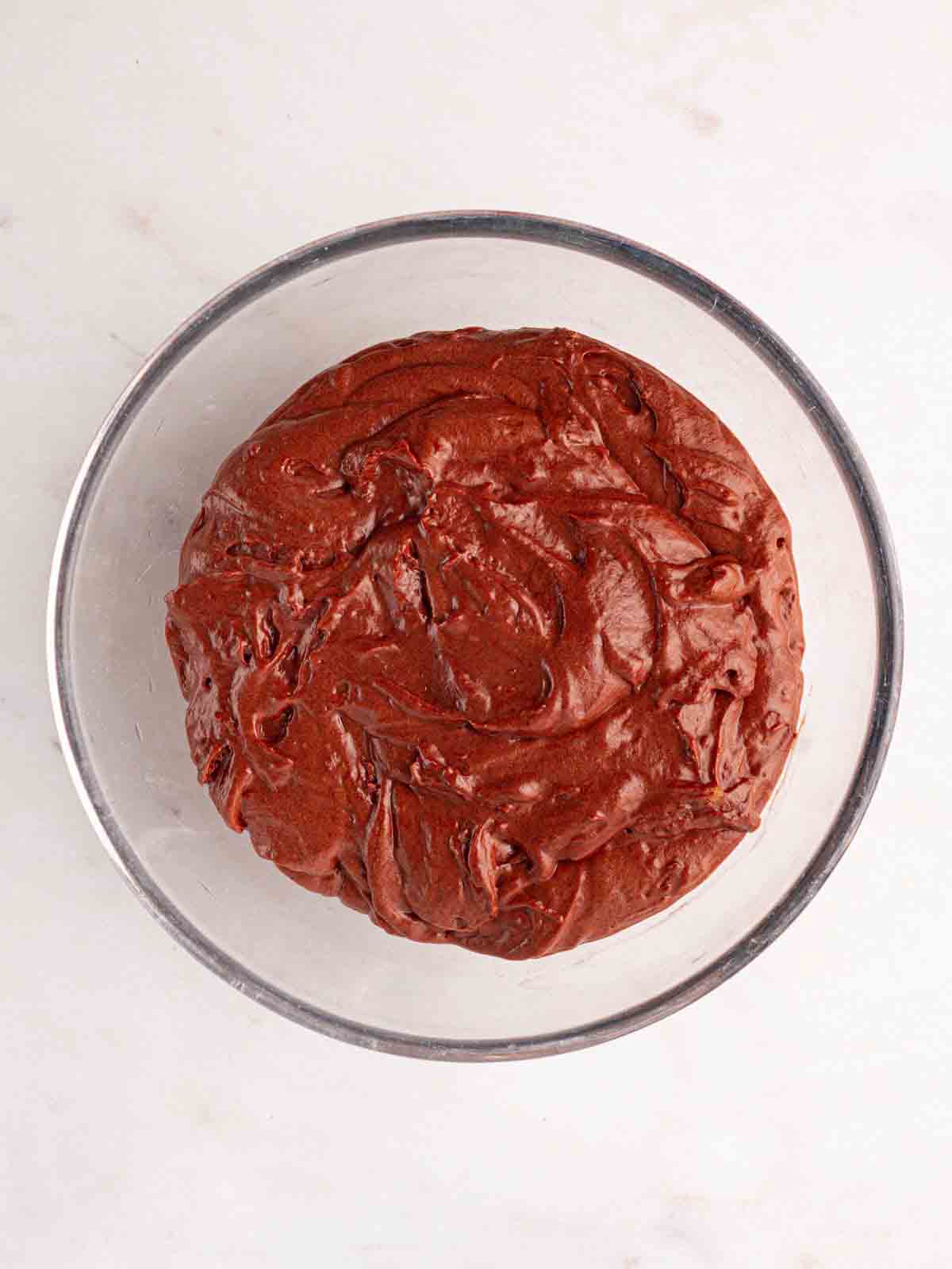A glass bowl on a white surface with a chocolate mixture for step 1 in the recipe for Slow Cooker Mini Egg Easter Pudding.