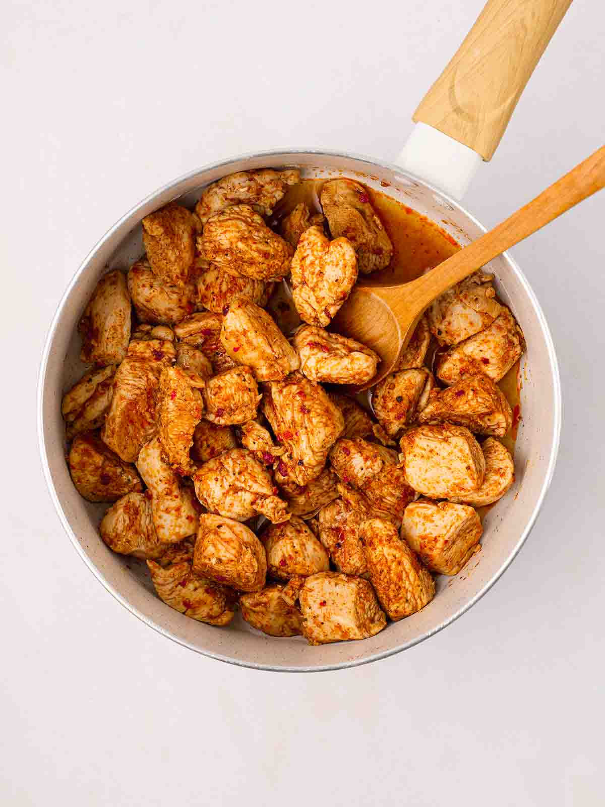 Chunks of chicken with cajun seasoning in a pan, cooking, for the recipe Cajun Chicken Pasta, step 1.