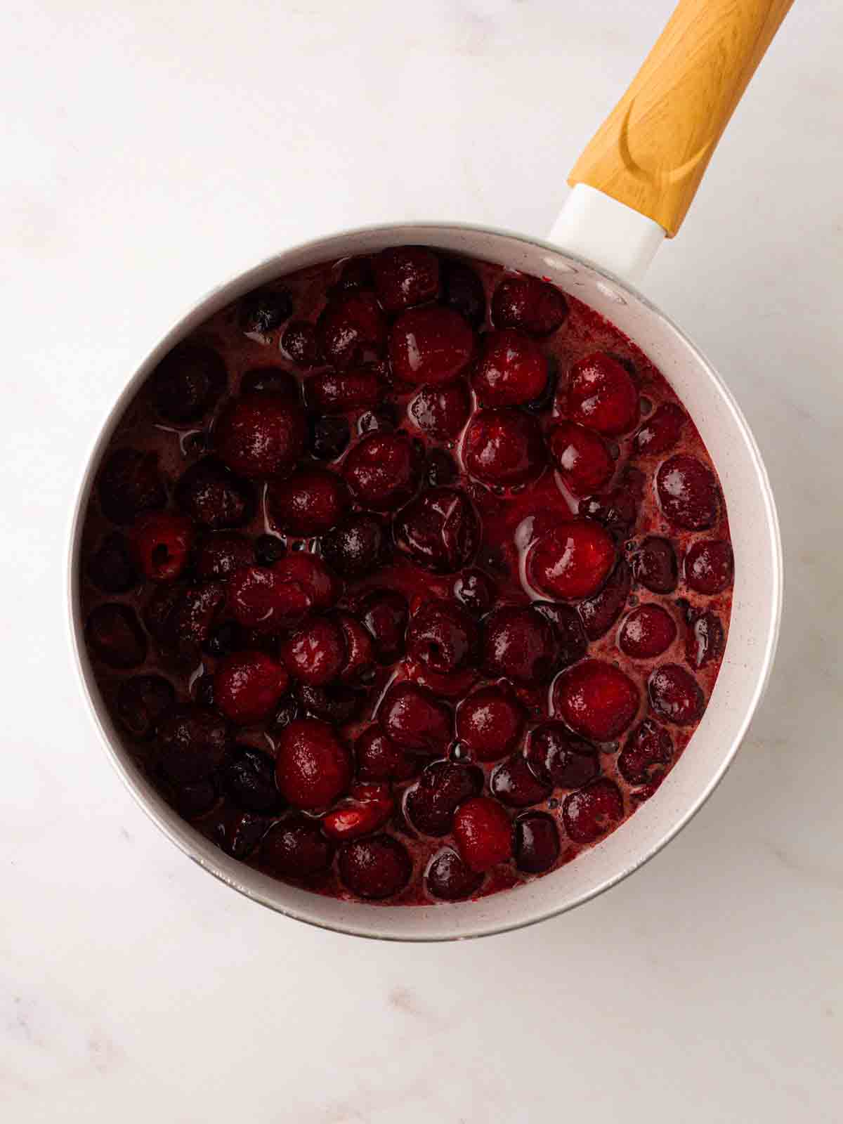 A pan filled with cherries in a juice for step 1 in the recipe for Cherry Pie.