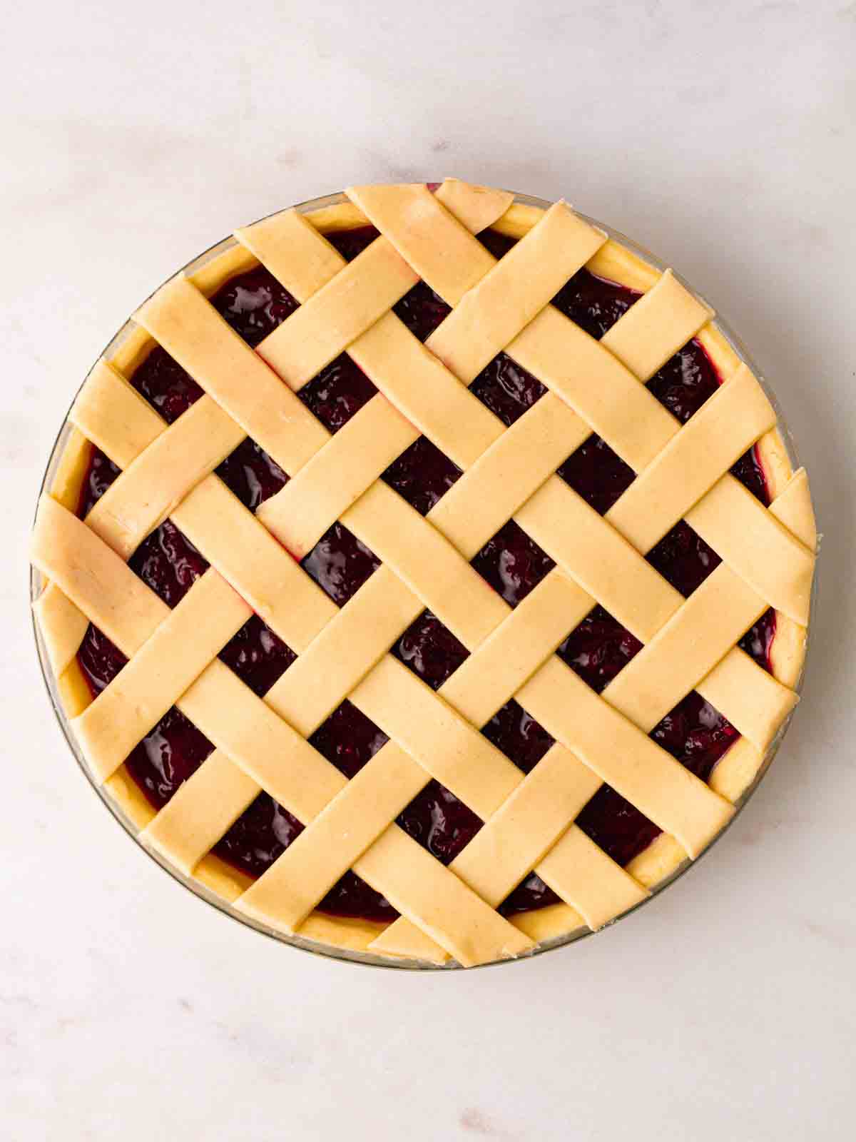 An uncooked cherry pie with a lattice top from a bird's eye view.