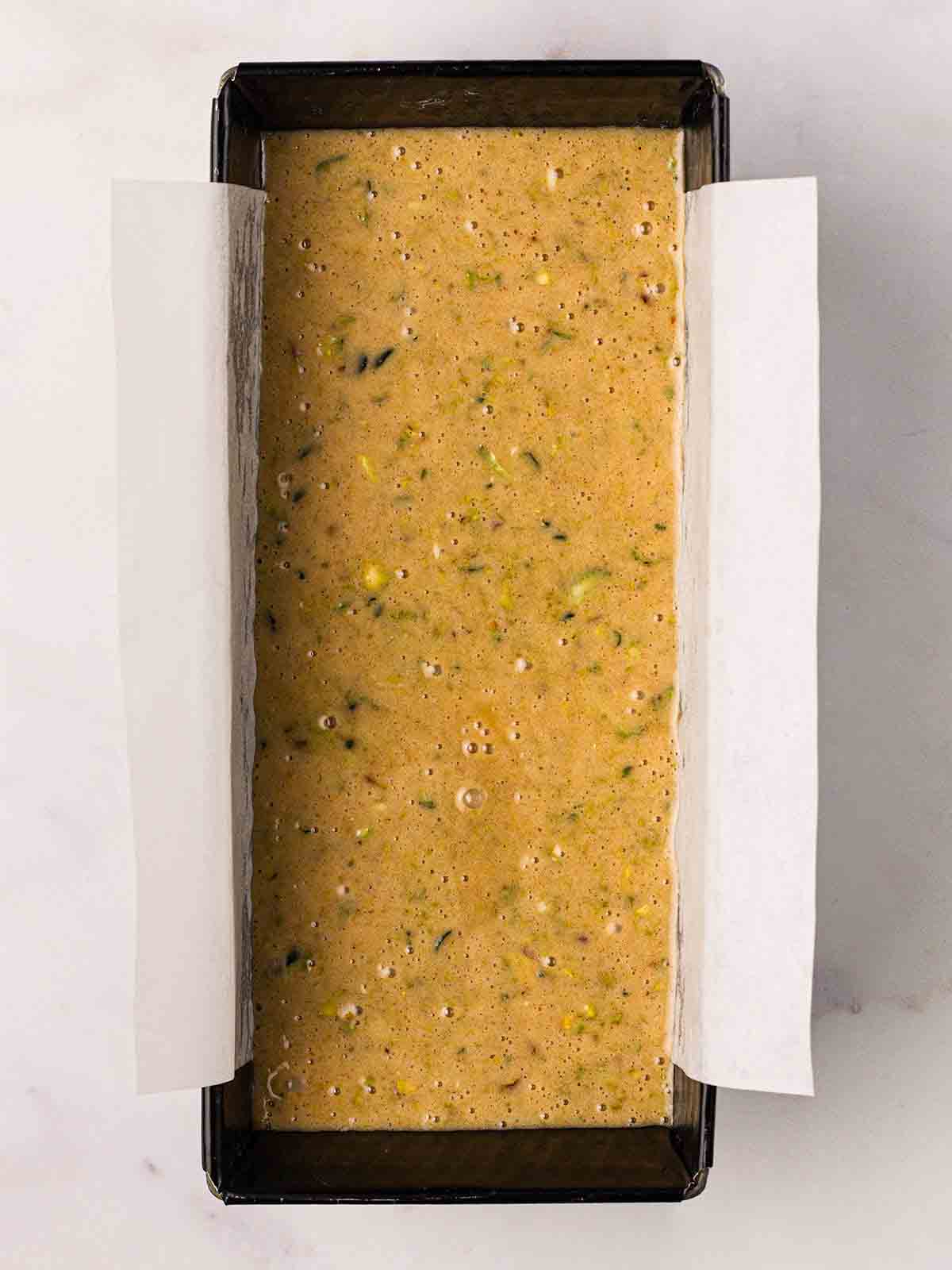 A loaf tin filled with Courgette Cake mixture, ready to be baked.