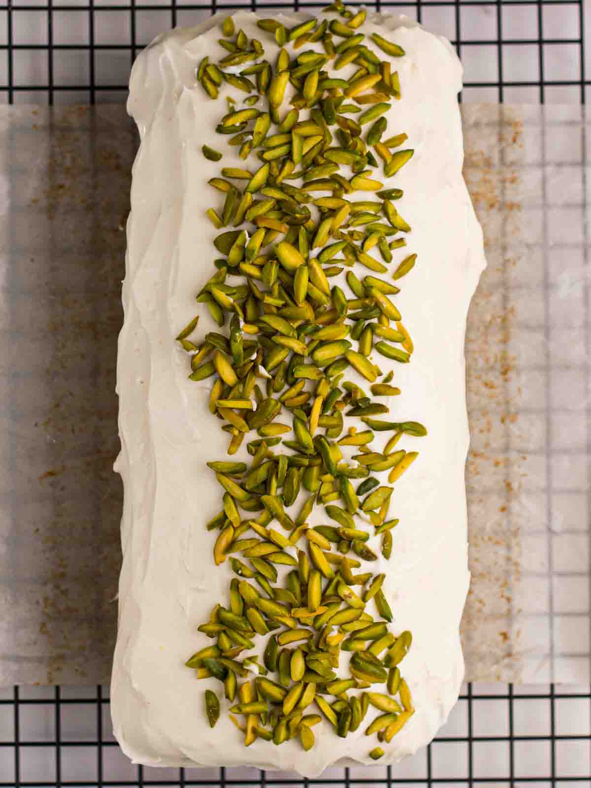 Bird's eye view of a finished and decorated Courgette Cake, with green pistachio flakes on top.
