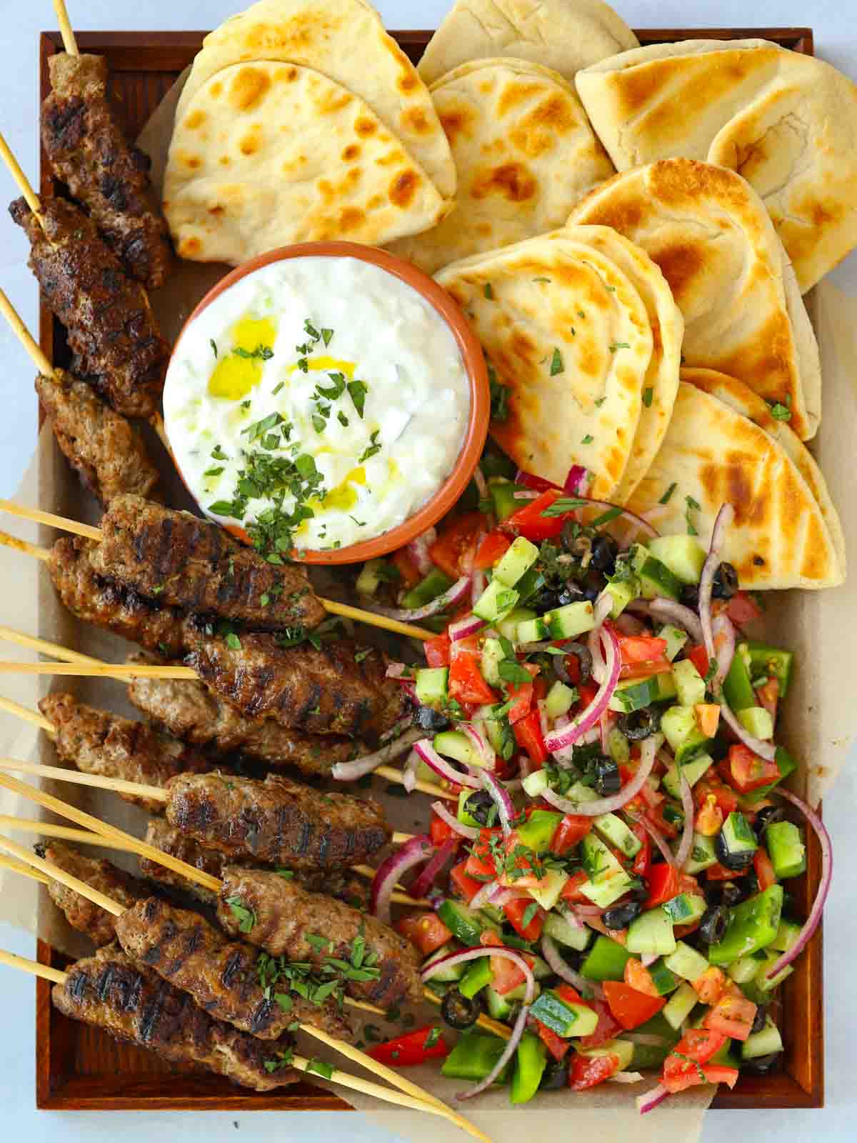 Lamb koftas recipe with meat mince and tzatziki, on a tray with flatbreads.