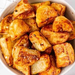 A close up of a bowl of golden and crispy air fryer roast potatoes.