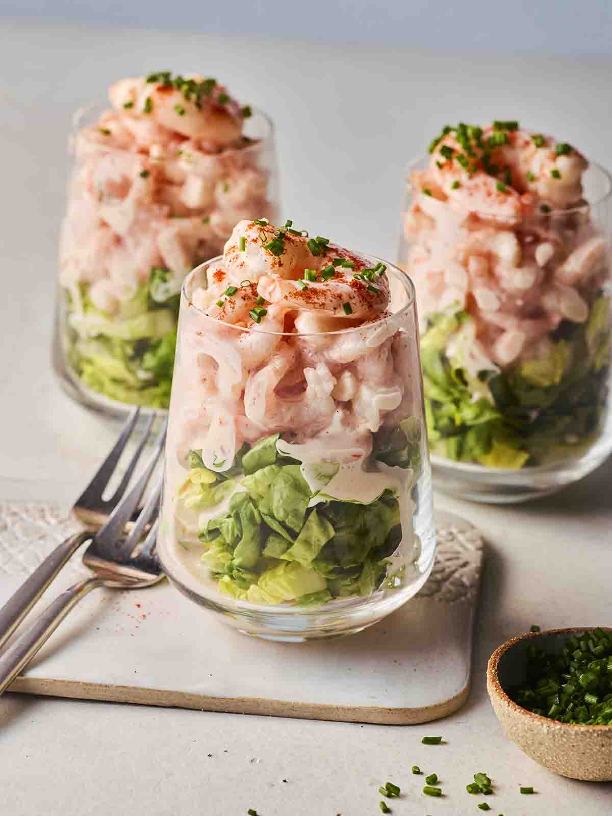 Three glasses with prawn cocktail inside, with forks to the side, ready to eat.