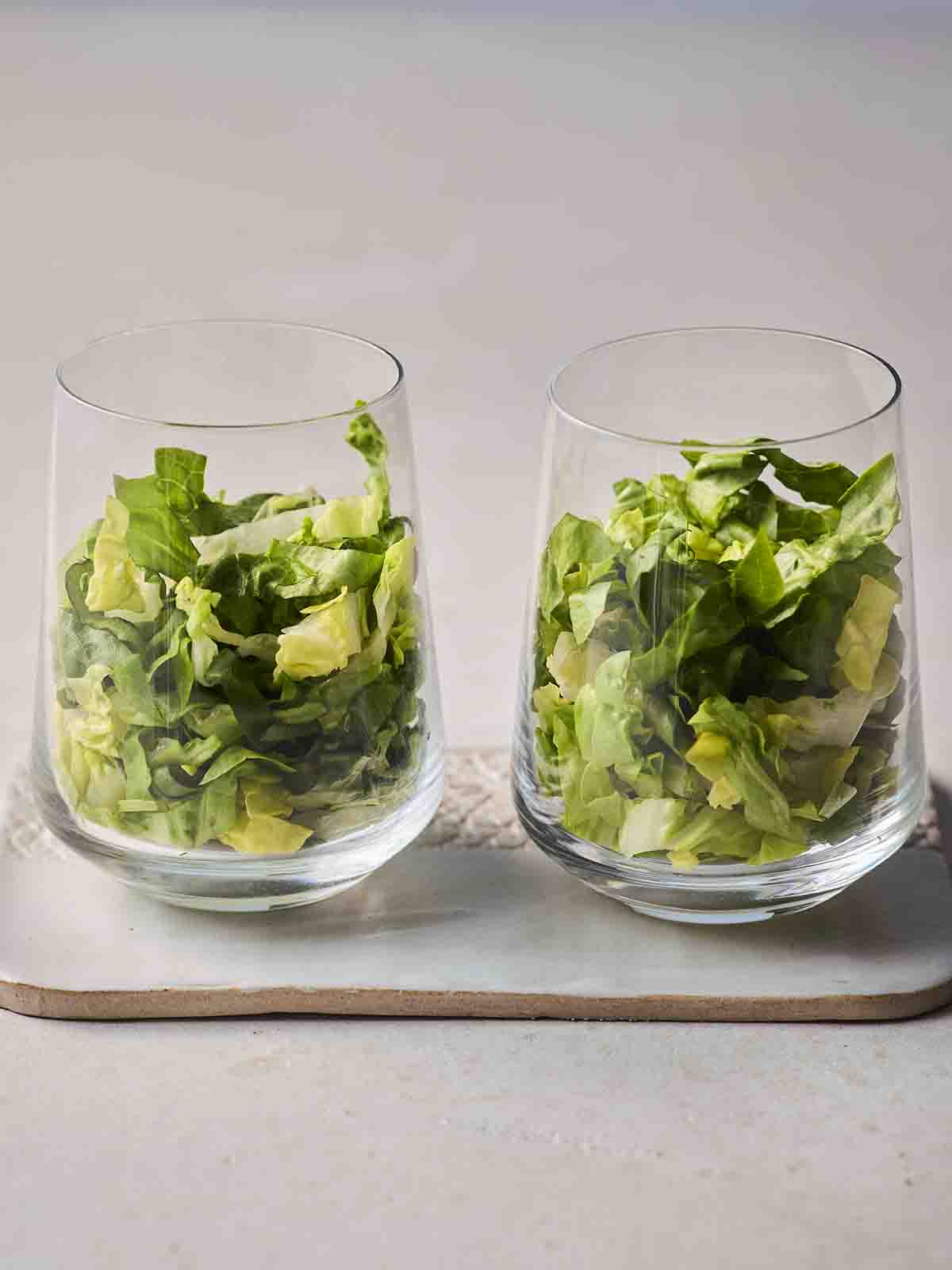 Two glasses half filled with shredded baby lettuce, for step 1 in the recipe for Prawn Cocktail.