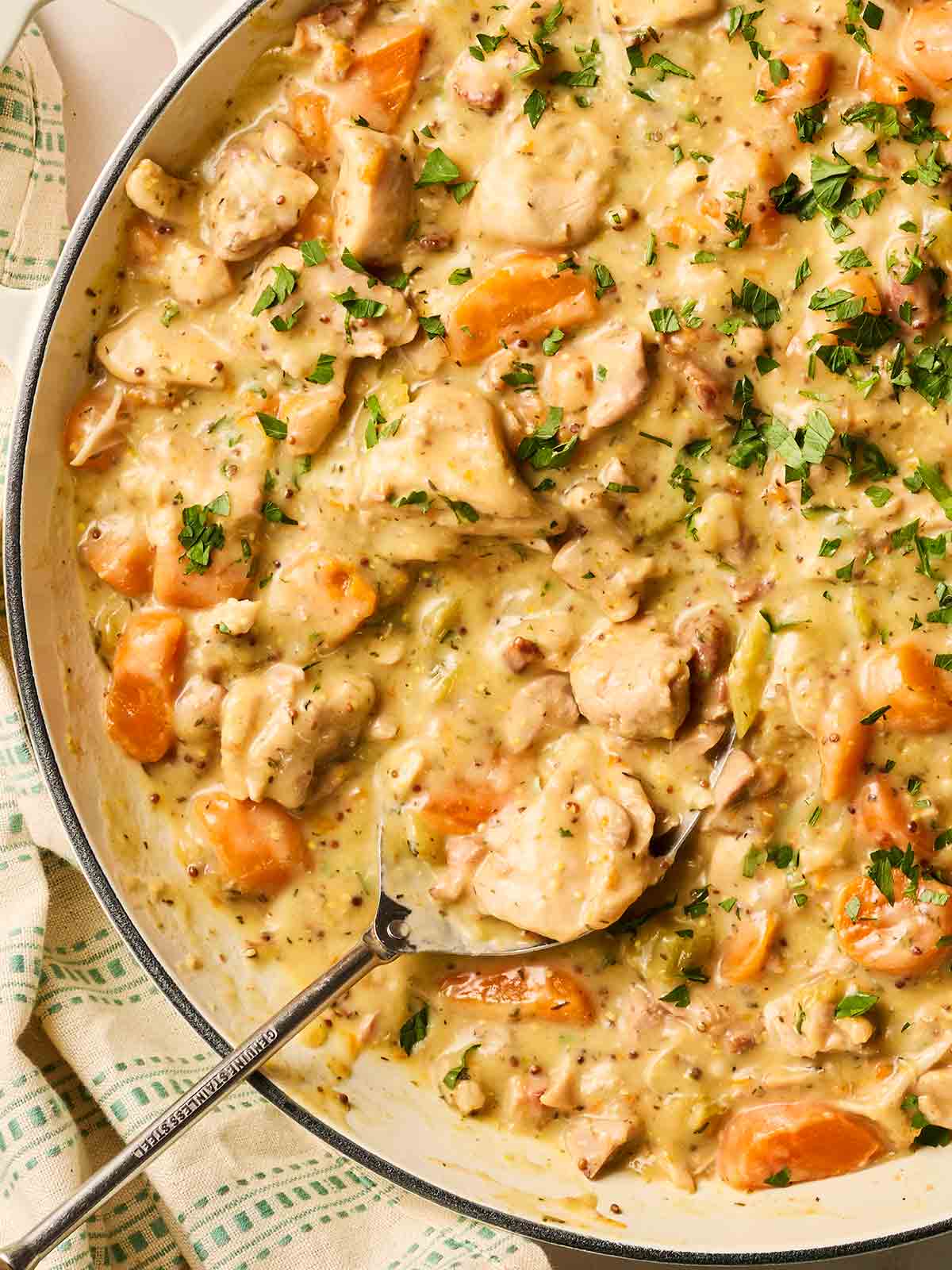 A spoon inside a pan of chicken casserole, ready to serve.