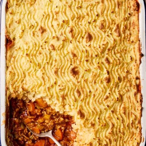 A comforting pie with mince and mashed potato, with a portion missing.