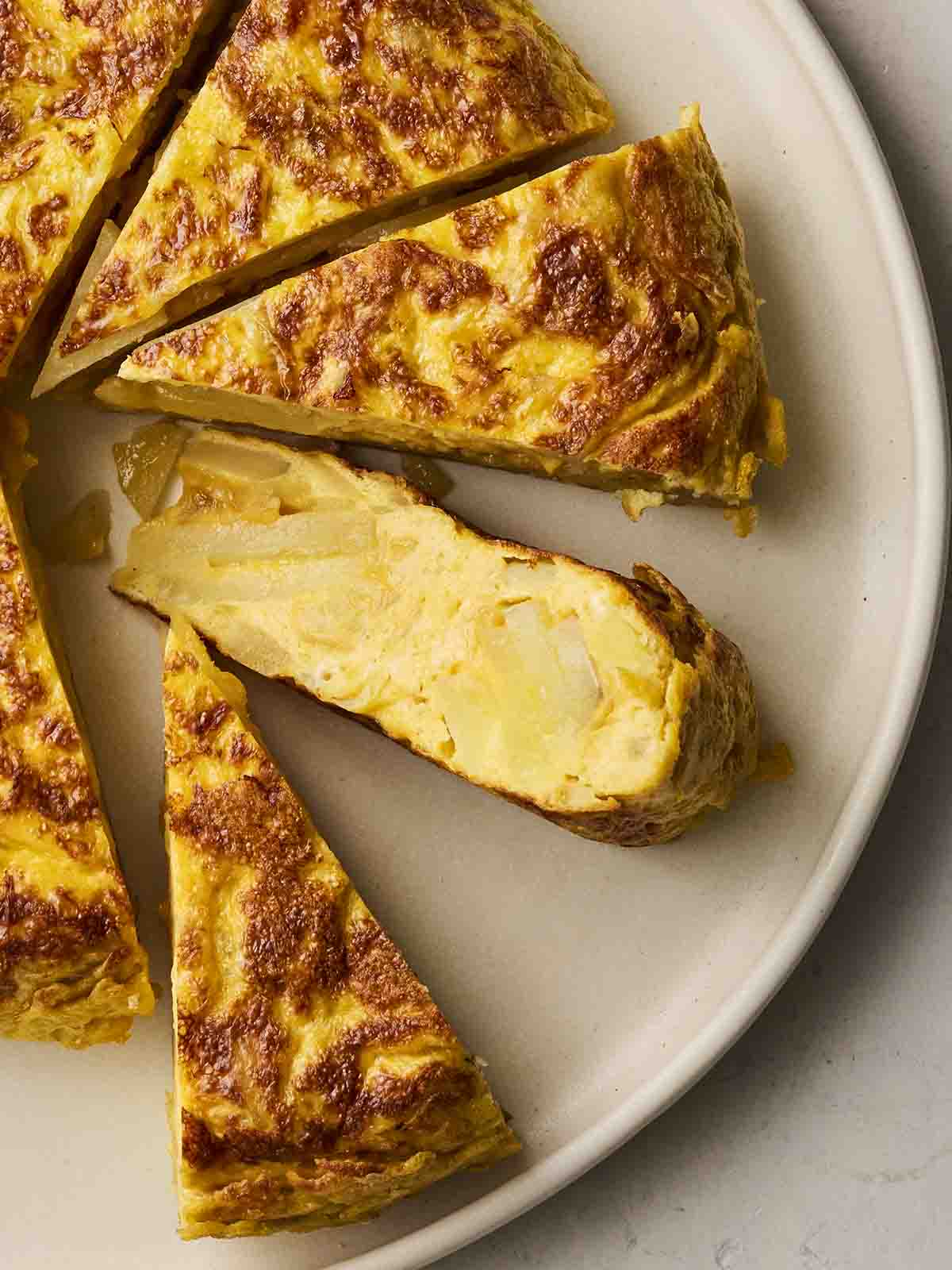 A close up of a sliced Spanish Omelette on a white plate.