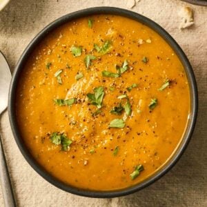 A close up of a bowl of orange Carrot and Coriander Soup.