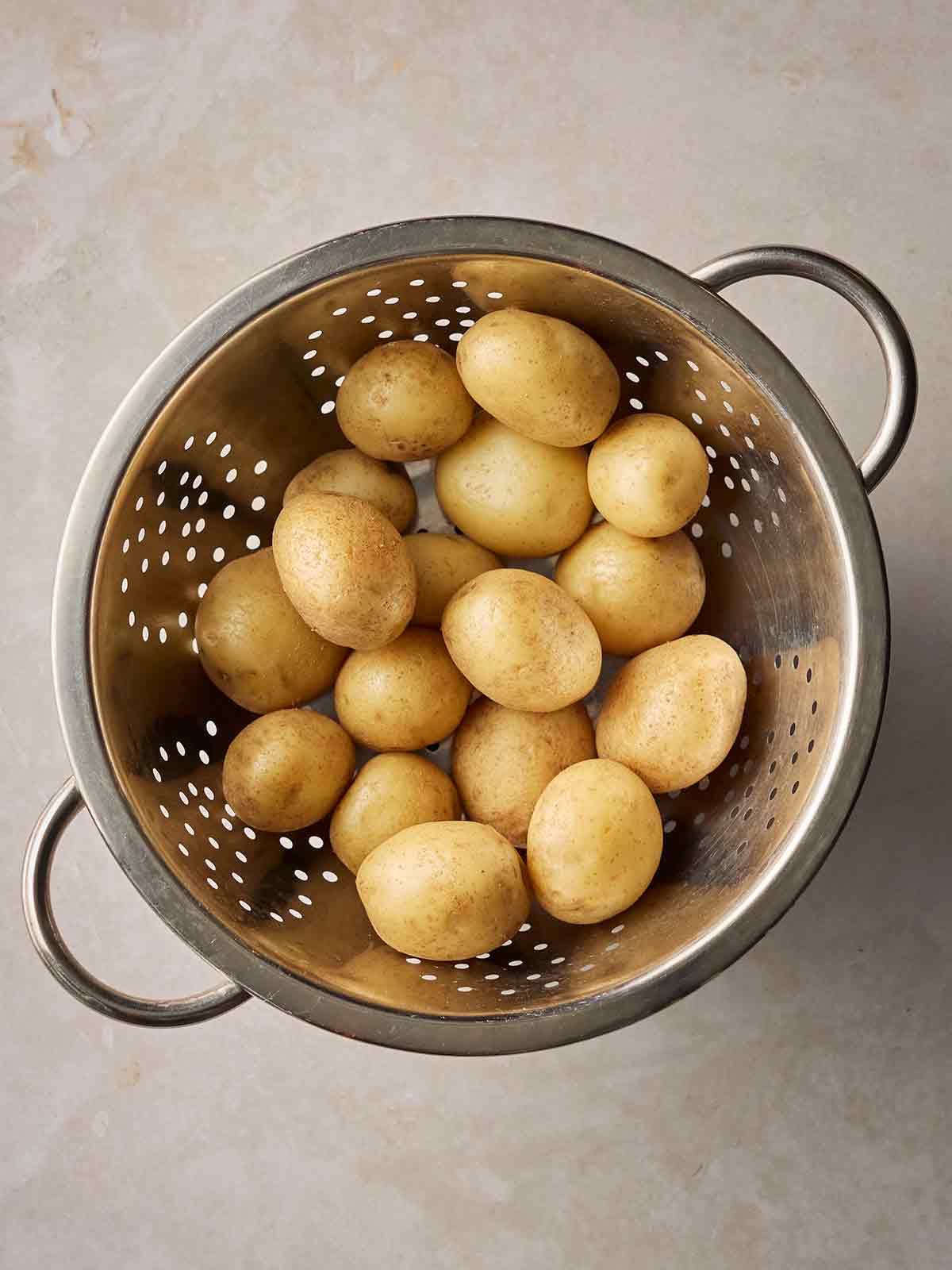 A colander with baby potatoes inside.