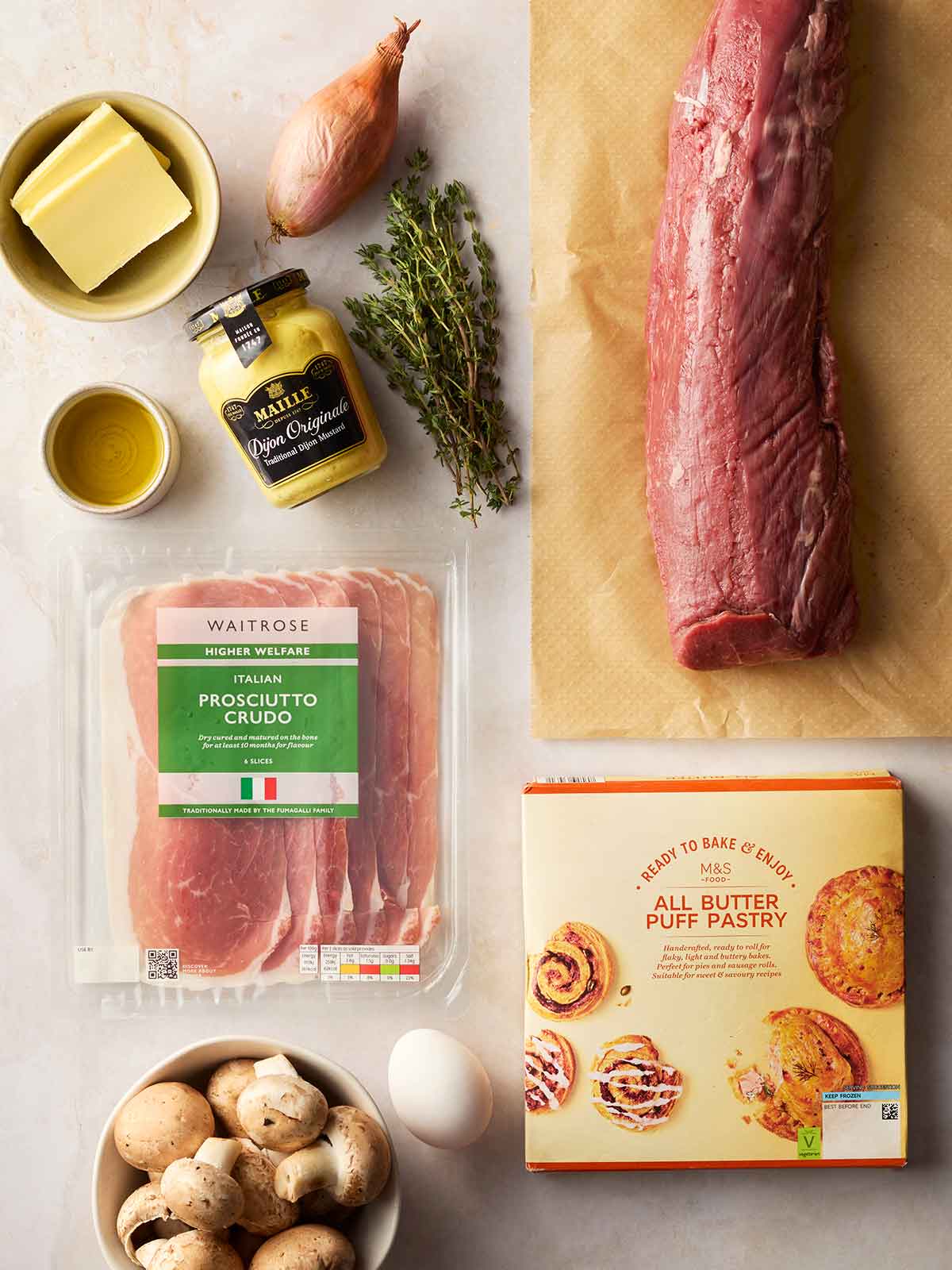 The raw ingredients for making a Beef Wellington laid out on a counter.