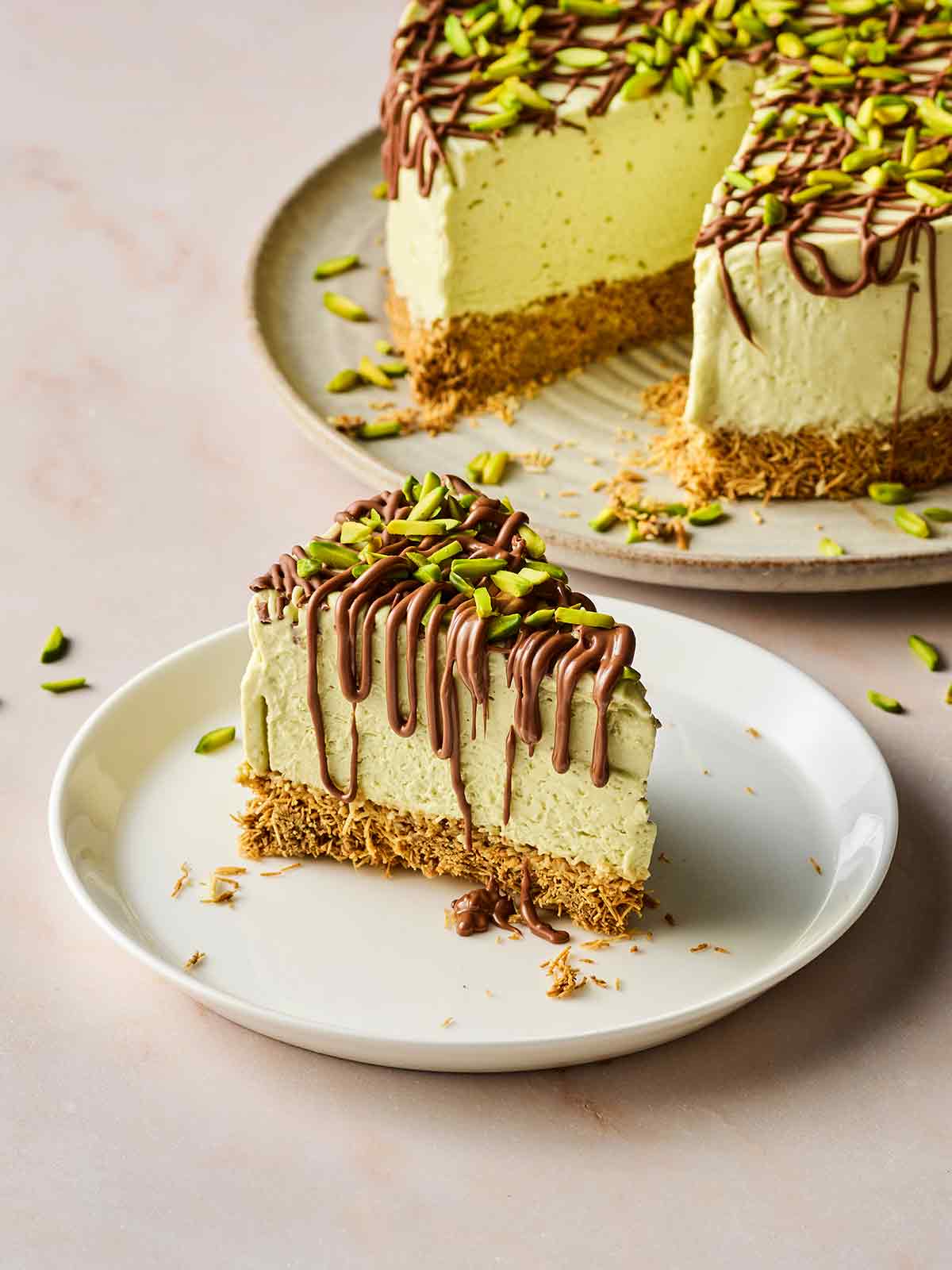 A slice of Dubai Chocolate Cheesecake on a plate, with the rest of the dessert in the background.