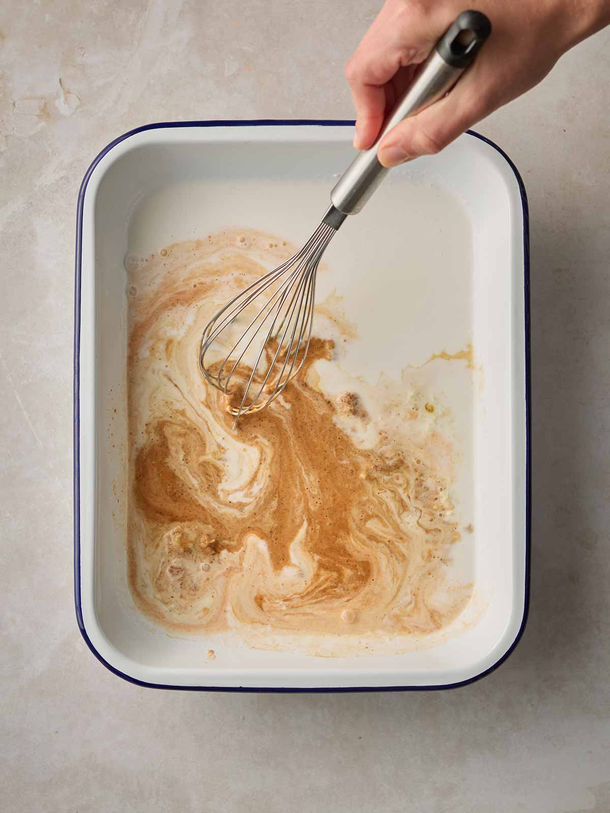 An oven dish with a whisk stirring a thai inspired sauce.