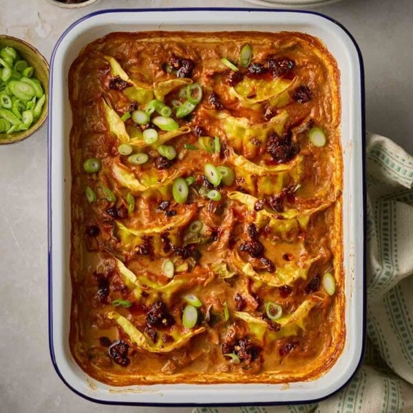 An oven dish with dumplings and vegetables in a red sauce on a table.