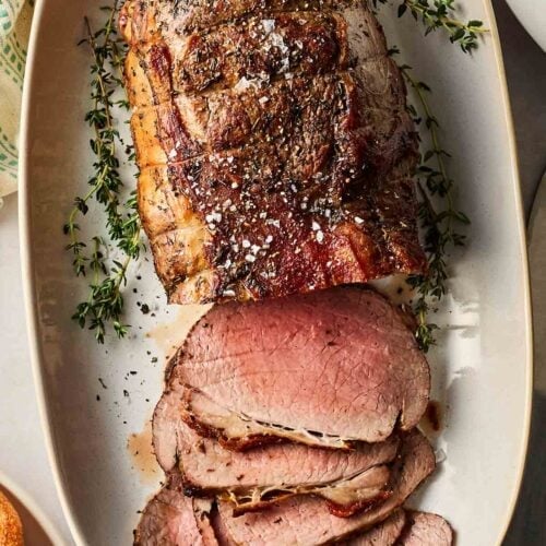 Beef roast on a platter with slices ready to eat.