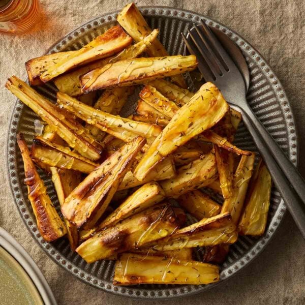 A bowl filled with golden roast parsnips, ready to serve.