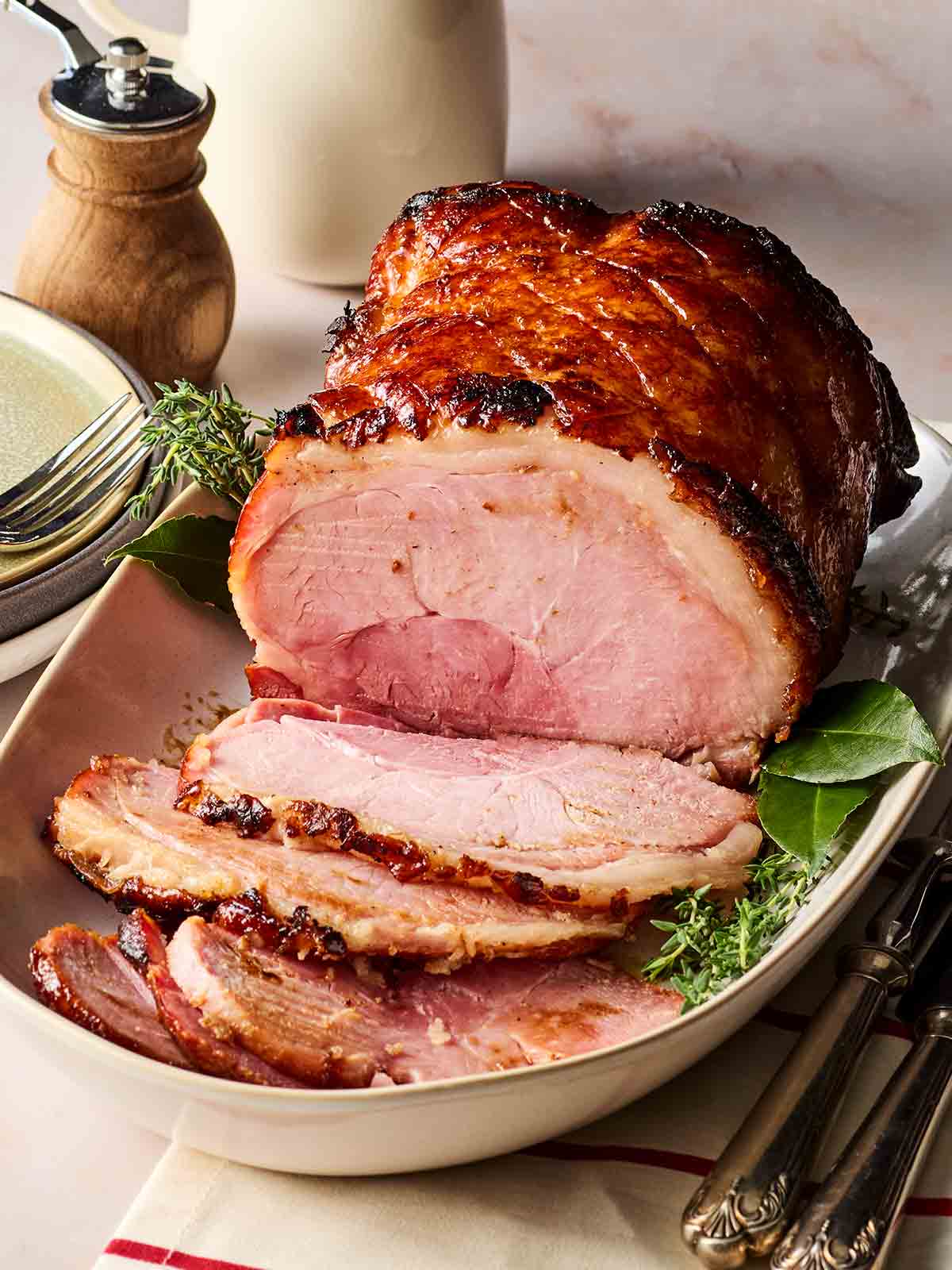 A table with a slow roasted gammon joint with a cider glaze on top, ready to dish out onto plates from the platter.