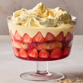 A traditional trifle in a glass dish on a white surface.