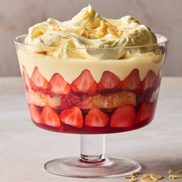 A traditional trifle in a glass dish on a white surface.