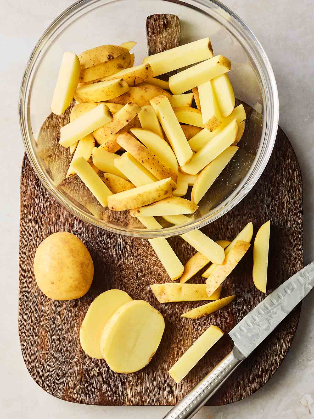 Hoemamde chips being cut with a knife and put in a glass bowl.
